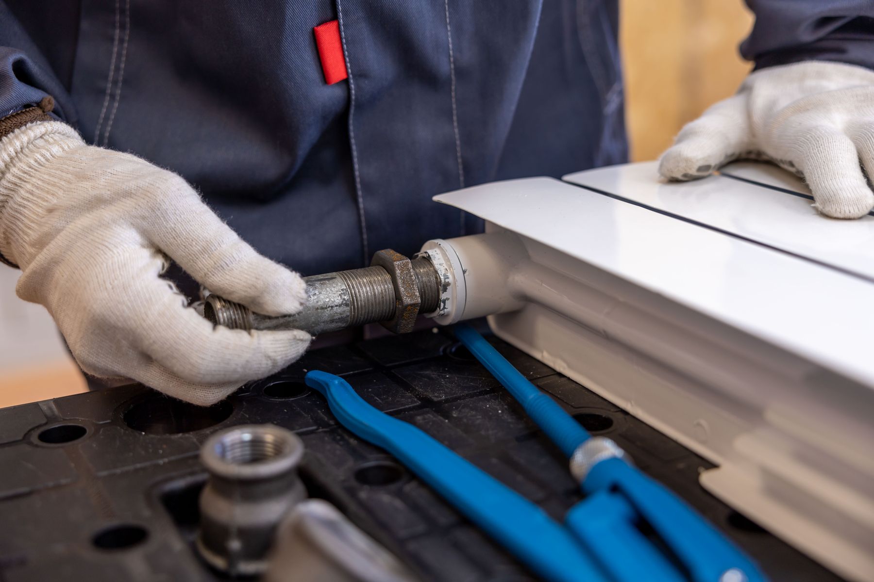 A plumber tightening a pipe joint with pliers